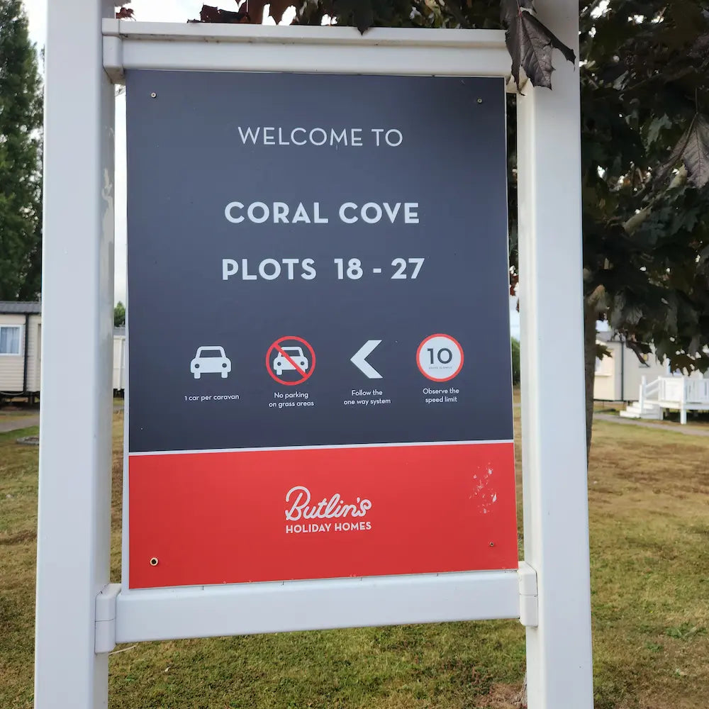 Welcome sign for Coral Cove plots 18-27 with Butlin's Holiday Homes branding.
