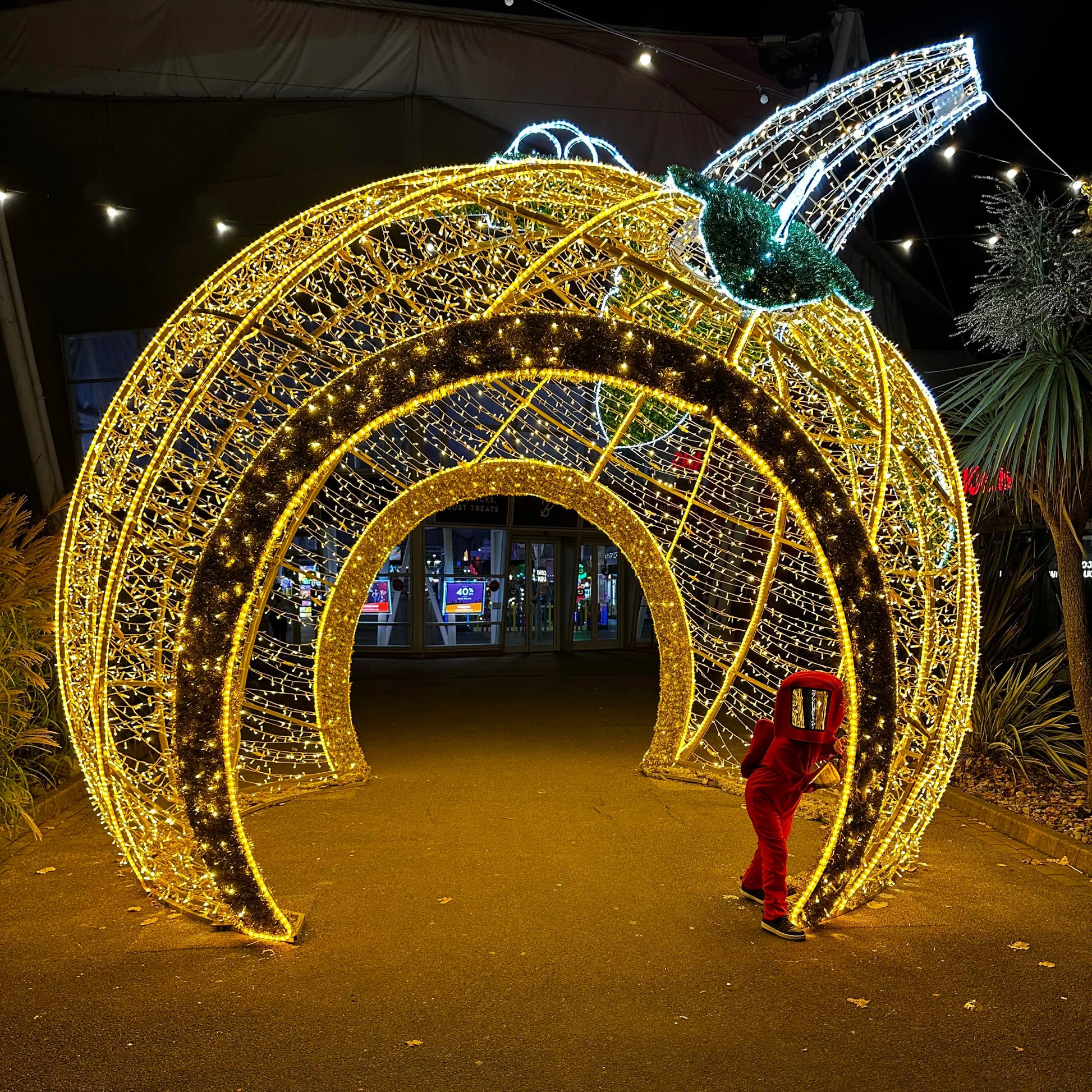 Decorative Halloween pumpkin archway with lights at night, person taking a photo of the Butlin's halloween decorations