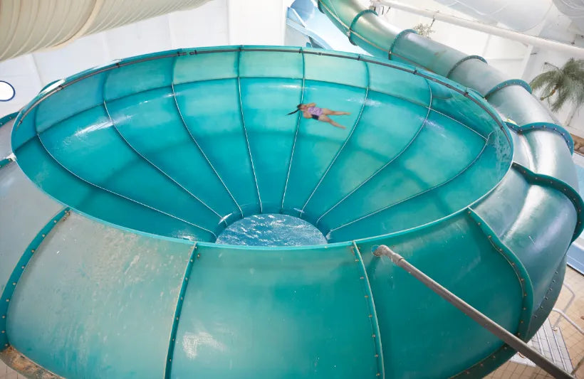 Large teal water slide at Splash waterworld with a person at the top, indoor setting