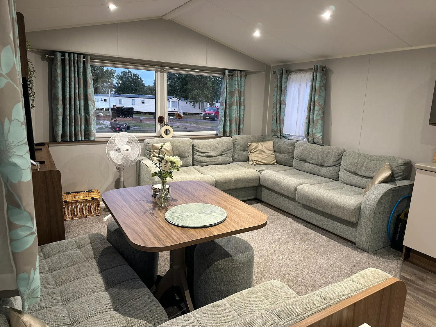 Butlins Caravan Living room with a sectional sofa, wooden table, and decorative items.
