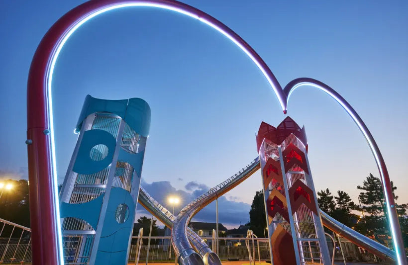 Children's playground with colorful slides and arches against a blue sky.